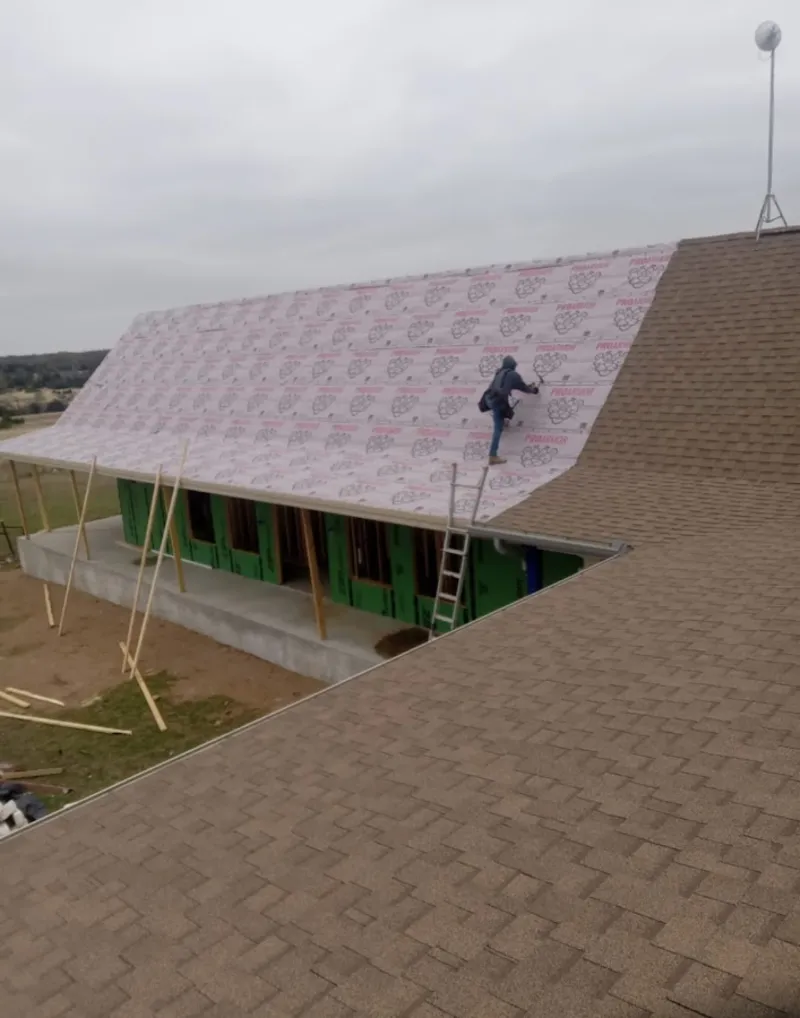 Worker preparing underlayment for a metal roof installation in Shively